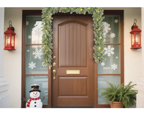 Versierde voordeur met guirlande, lantaarns, sneeuwvlokstickers en sneeuwpop