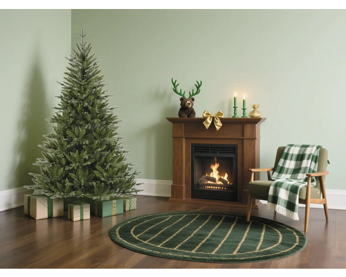 Woonkamer met kerstboom, open haard en fauteuil voor een feestelijke sfeer