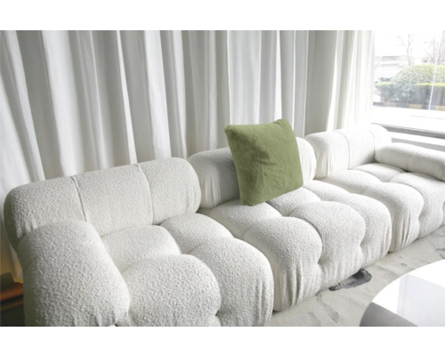 Witte modulaire bank met kussen en structuurhoes voor een raam met gordijnen