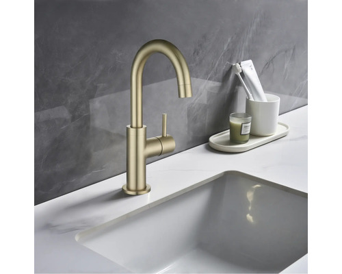 Gouden kraan met ronde uitloop en zijhendel op de wastafel