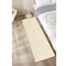 Beige loper voor een bed op een houten vloer