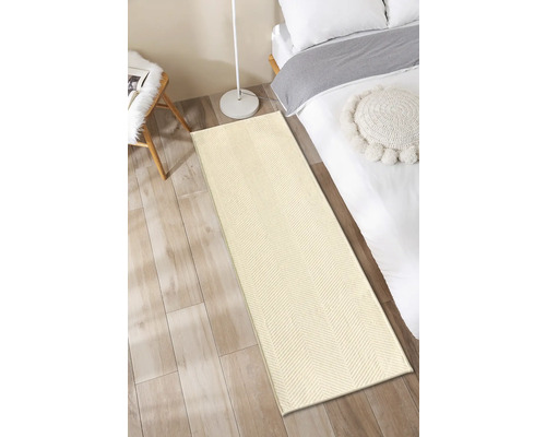 Beige loper voor een bed op een houten vloer