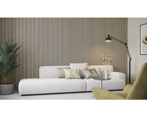 Woonkamer met houten lambrisering, bank, staande lamp en kamerplant.