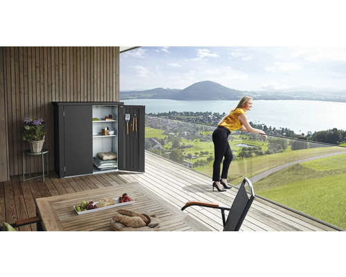 Scene met een gereedschapskast met open deuren op een terras met uitzicht op het meer