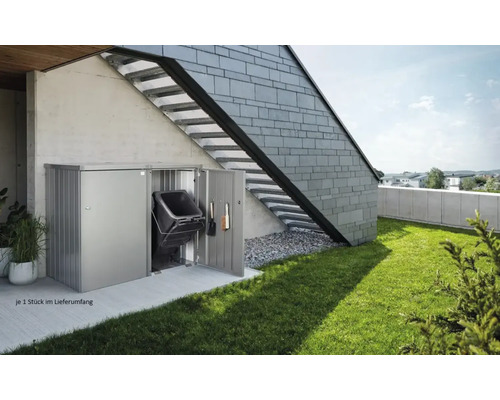 Metalen afvalcontainerbox met vuilnisbak en tuingereedschap tegen een huiswand met buitentrap