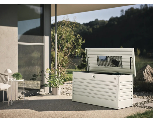 Geopende metalen tuinkist op een terras met uitzicht op de tuin