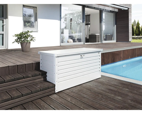 Foto van een witte metalen opbergbox op een terras naast een zwembad.