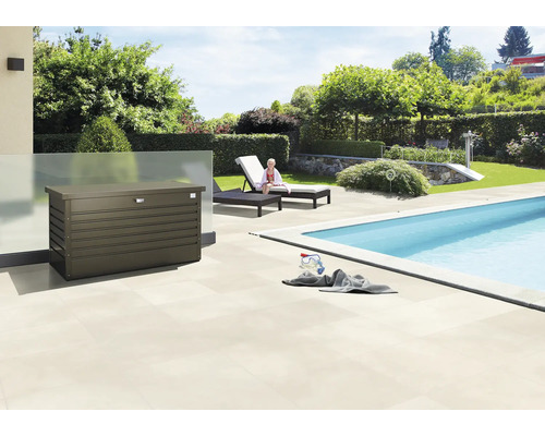 Buitenscène met een opbergbox naast een zwembad, ligstoelen en een tuin.