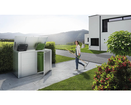 Metalen afvalcontainerbox met twee vuilnisbakken en een vrouw met een hark in de tuin