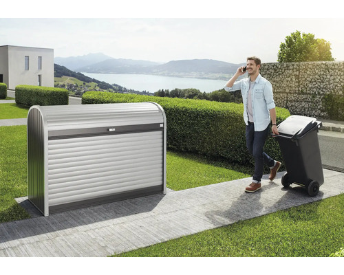 BIOHORT Containerberging StoreMax 160 donkergrijs metallic 163x78x120 cm Metalen afvalcontainerbox met rolluik in de tuin, man telefoneert en trekt vuilnisbak