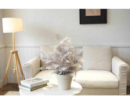 Decoratieve kunstmatige varen in pot op een tafel voor een bank