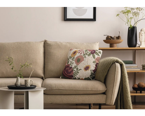 Woonkamer scene met beige bank, bloemendecoratiekussen en bijzettafel