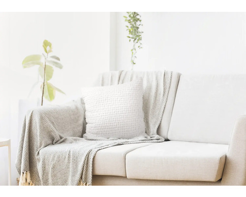 Lichte woonkamer met bank, kussen en sprei