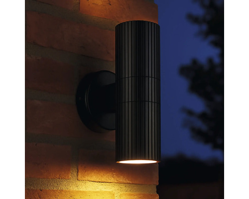 Zwarte buitenwandlamp met geribbelde lampbehuizing op een bakstenen muur