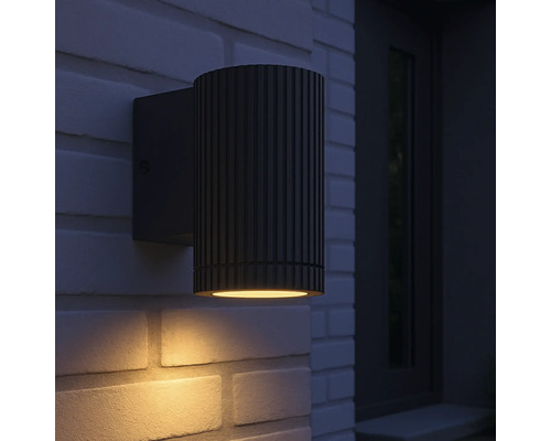 Een zwarte buitenwandlamp is gemonteerd op een bakstenen muur.
