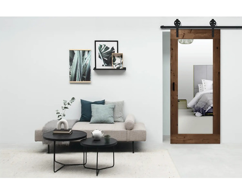 Woonkamer met houten schuifdeur en spiegel, bank, salontafels en decoraties