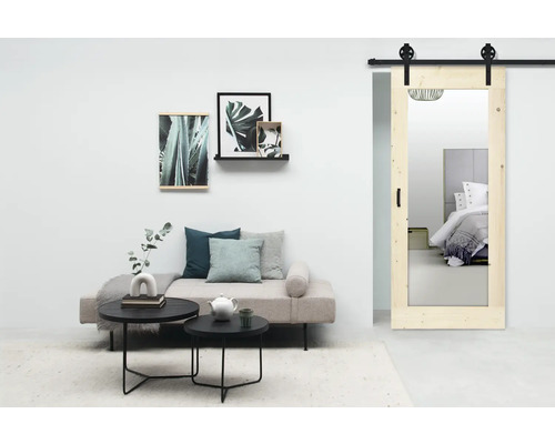 Woonkamer met spiegelende schuifdeur, bank en salontafels.