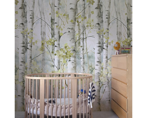 Kinderkamer met een behang met berkenmotief, een rond babybed en een commode