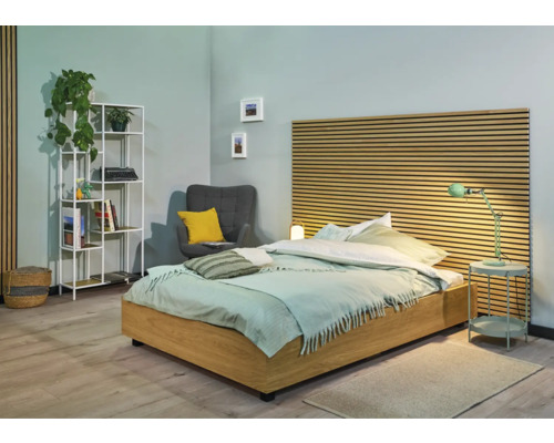 Lichte slaapkamer met bed, nachtkastje, rek en fauteuil