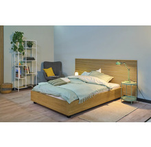 Lichte slaapkamer met houten bed, nachtkastlamp, plank en fauteuil