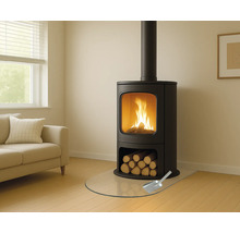 Houtkachel met brandhout, glazen beschermplaat en schep in een woonkamer.