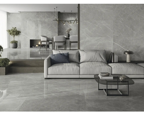 Lichte woonkamer met vloertegels en wandtegels in marmerlook, met bank, tafel en open haard.