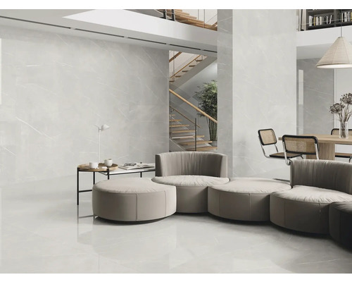 Lichte woonkamer met grote tegels op de vloer en wand, trap op de achtergrond