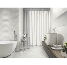 Lichte badkamer met vrijstaand bad, wastafel en gestructureerde wandtegels voor een modern design.