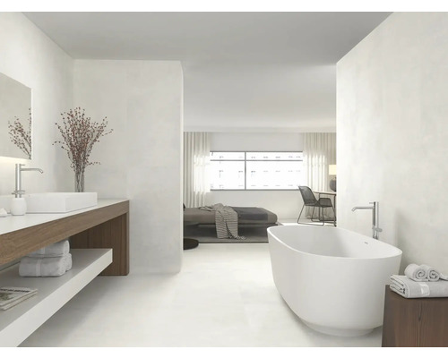 Lichte badkamer met bad, wastafel en toegang tot de slaapkamer