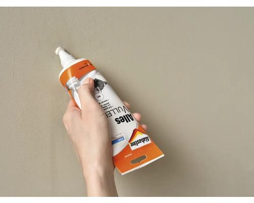 Een hand vult een gat in de muur met Allesvuller van Alabastine