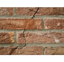 Close-up van een bakstenen muur met scheuren in het metselwerk