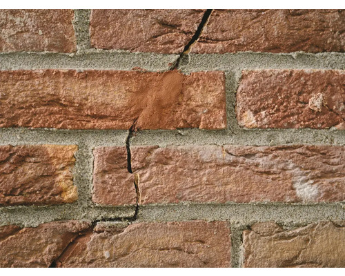Close-up van een bakstenen muur met scheuren in het metselwerk