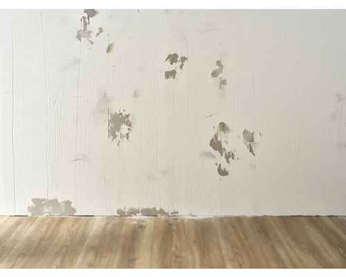 Muur met reparatiewerkzaamheden en houten vloer voor renovatieprojecten.