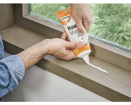 Een man brengt Alabastine huisvuller aan op een vensterbank.