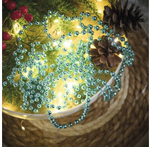 Decoratie met ballenketting, dennentakken, rode bessen, lichtsnoer en dennenappels in een schaal