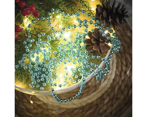 Decoratie met ballenketting, dennentakken, rode bessen, lichtsnoer en dennenappels in een schaal