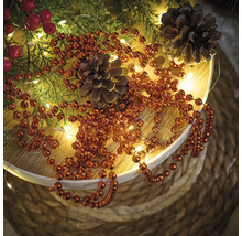 Decoratie met dennenappels, dennengroen, rode bessen, lichtslinger en kralenketting
