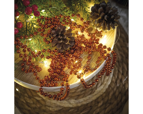 Decoratie met dennenappels, dennengroen, rode bessen, lichtslinger en kralenketting