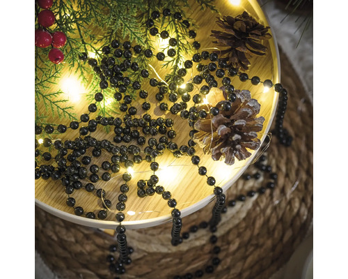 Decoratief dienblad met lichtjesslinger, dennentakken, dennenappels en kralenketting