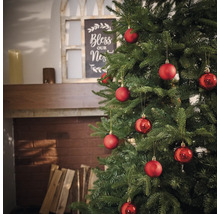 Versierde kerstboom met rode ballen in de woonkamer.