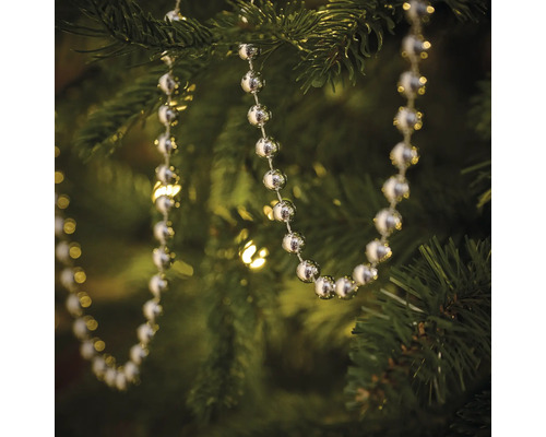 Zilverkleurige kralenketting als boomversiering in een kerstboom