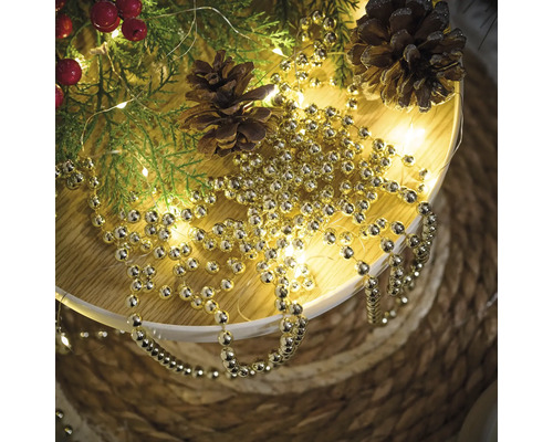 Decoratie met takken van de spar, dennenappels en een goudkleurige ballenslinger