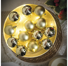 Decoratieve goudkleurige kerstballen op een schaal met lichtjes