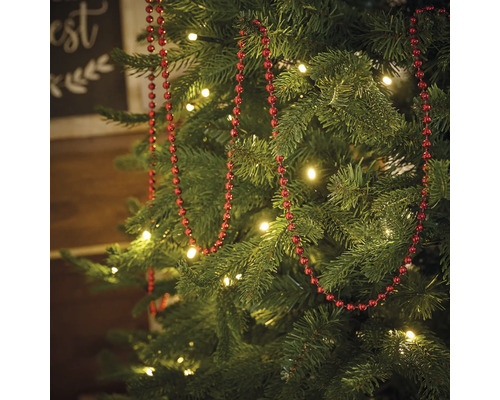 Versierde kerstboom met rode kralenketting en verlichting