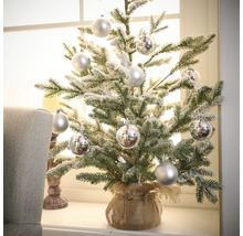 Kleine kerstboom met decoratieve ballen in jute zak