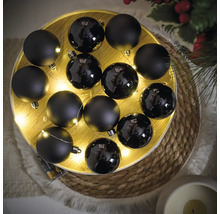 Arrangement van zwarte kerstballen met matte en glanzende afwerking, aangevuld met een lichtslinger op een rond dienblad