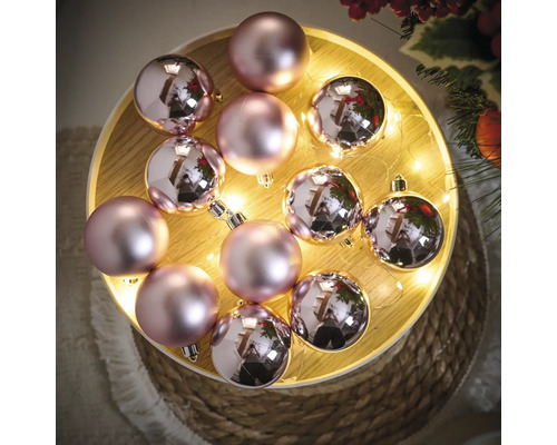 Decoratieve roze kerstballen op een verlicht dienblad.
