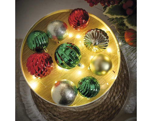 Decoratieve kerstballen in groen, zilver en rood op een versierde tafel.