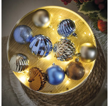 Veelkleurige kerstballen op een verlicht houten dienblad