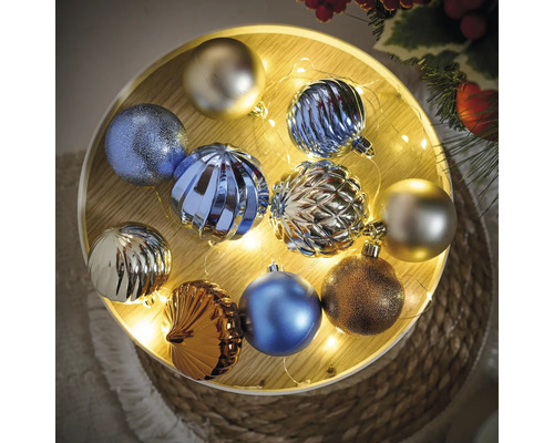 Veelkleurige kerstballen op een verlicht houten dienblad